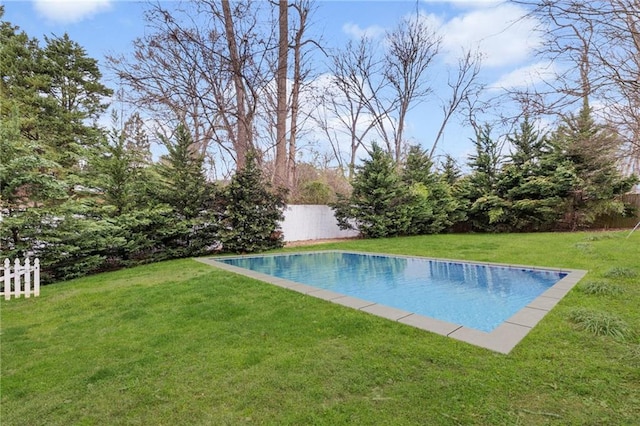 outdoor pool featuring fence and a yard