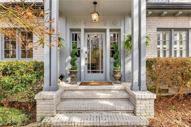 entrance to property featuring covered porch and brick siding