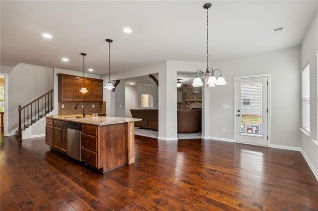 kitchen with dark hardwood / wood-style flooring, stainless steel dishwasher, backsplash, light stone countertops, and pendant lighting