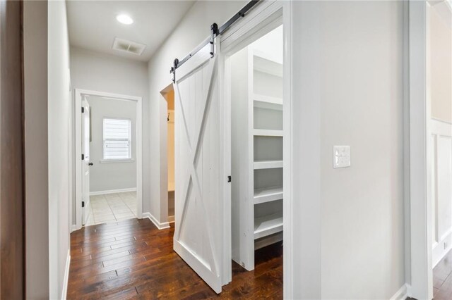 corridor with dark hardwood / wood-style flooring and a barn door