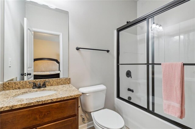 full bathroom with toilet, vanity, and bath / shower combo with glass door