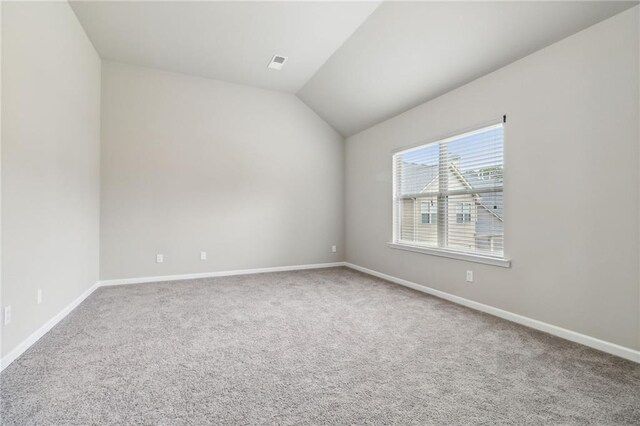 carpeted spare room featuring vaulted ceiling