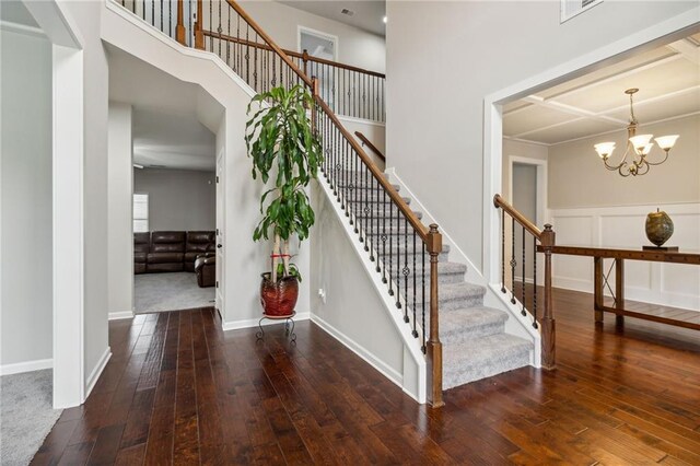 stairway featuring a high ceiling, hardwood / wood-style flooring, and a notable chandelier