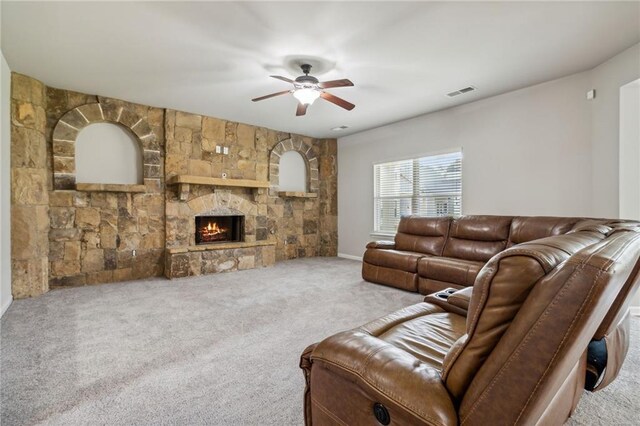 carpeted living room featuring ceiling fan and a fireplace