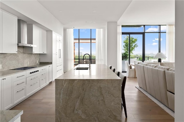 2425 Peachtree Rd NE Unit 1503, Atlanta, GA 30305 - kitchen with wall chimney range hood, a sink, a wall of windows, cooktop, and tasteful backsplash