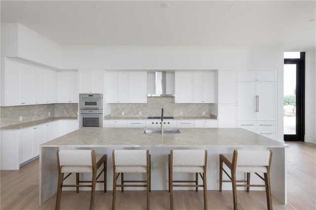 2425 Peachtree Rd NE Unit 1503, Atlanta, GA 30305 - kitchen with wall chimney exhaust hood, double wall oven, tasteful backsplash, a sink, and white cabinets