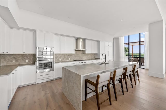 2425 Peachtree Rd NE Unit 1503, Atlanta, GA 30305 - kitchen with a sink, wall chimney range hood, stainless steel double oven, white cooktop, and decorative backsplash