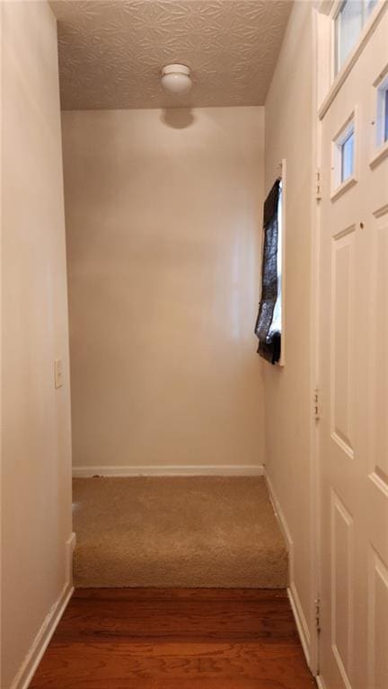 hall featuring a textured ceiling and dark wood-type flooring