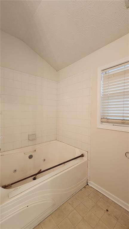 bathroom featuring lofted ceiling, tile patterned floors, and washtub / shower combination