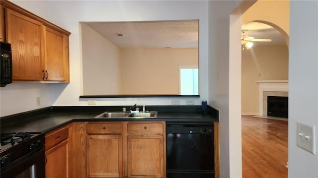 kitchen with light hardwood / wood-style flooring, a high end fireplace, sink, black appliances, and ceiling fan