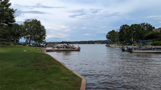 view of dock with a lawn and a water view