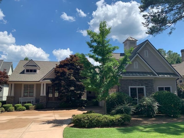 craftsman house with a standing seam roof, metal roof, stone siding, and french doors