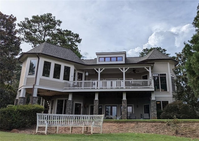 rear view of property featuring stone siding, ceiling fan, and a balcony