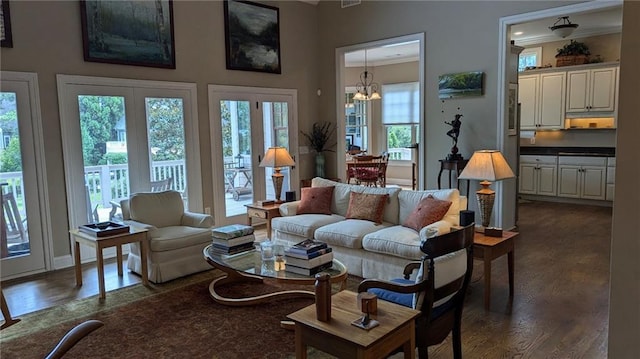 living room featuring dark wood-type flooring, ornamental molding, and a notable chandelier