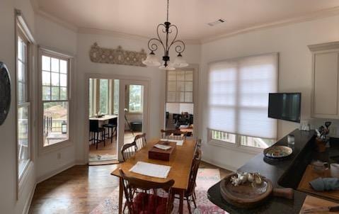 dining space with visible vents, ornamental molding, and a chandelier