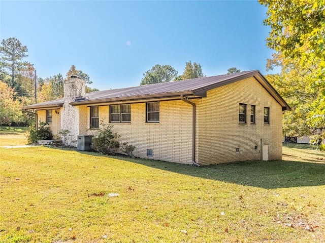 back of property with crawl space, brick siding, a lawn, and a chimney