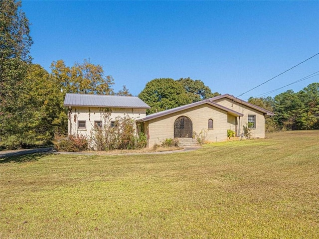 view of front of home with metal roof and a front lawn