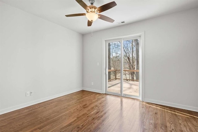 spare room with visible vents, ceiling fan, baseboards, and wood finished floors