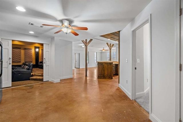 interior space with concrete flooring, a ceiling fan, visible vents, and baseboards