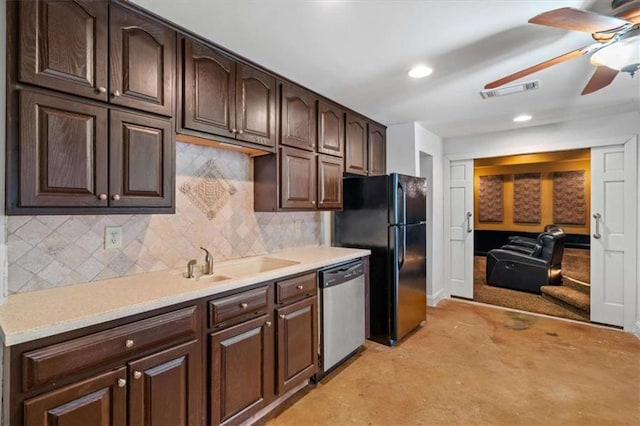 kitchen featuring dark brown cabinetry, light countertops, stainless steel dishwasher, and freestanding refrigerator