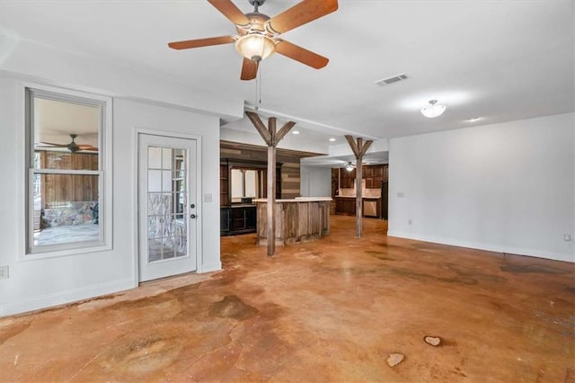 unfurnished living room featuring visible vents, concrete floors, baseboards, and ceiling fan