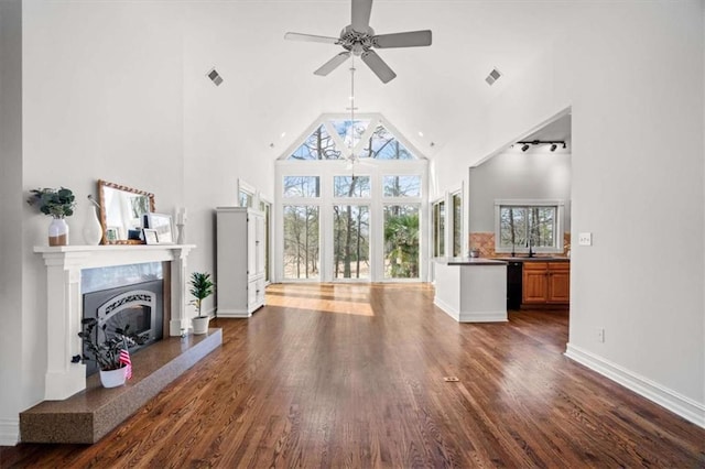 living area featuring visible vents, a premium fireplace, high vaulted ceiling, and dark wood finished floors