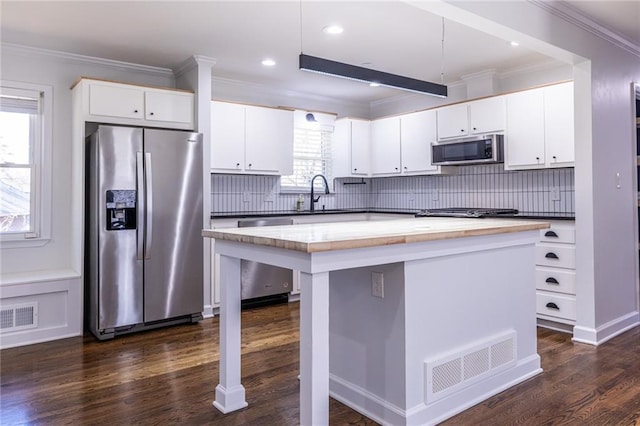 kitchen featuring a kitchen island, visible vents, white cabinetry, appliances with stainless steel finishes, and dark countertops