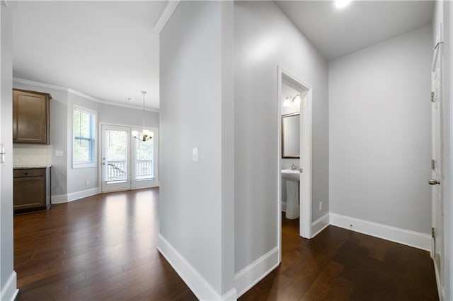 hall with ornamental molding, an inviting chandelier, and dark wood-type flooring