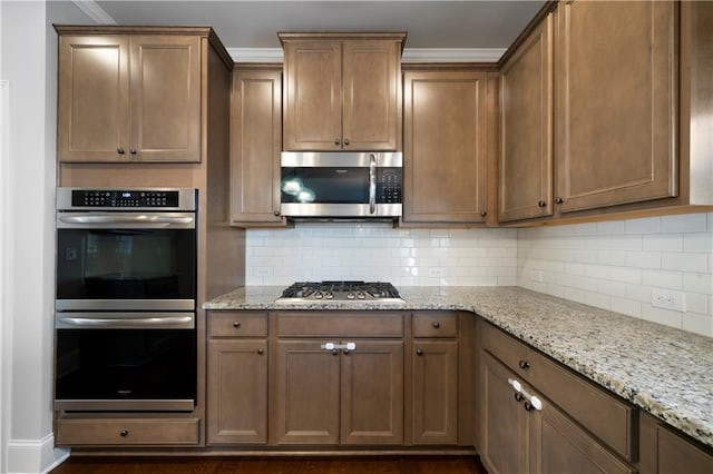 kitchen featuring dark hardwood / wood-style floors, light stone countertops, appliances with stainless steel finishes, and tasteful backsplash