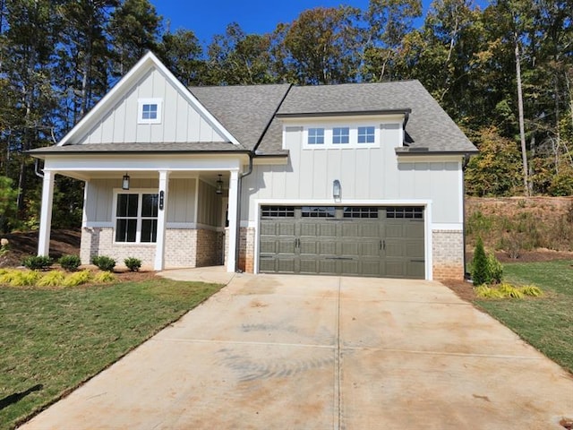 modern farmhouse with board and batten siding, concrete driveway, brick siding, and a front lawn