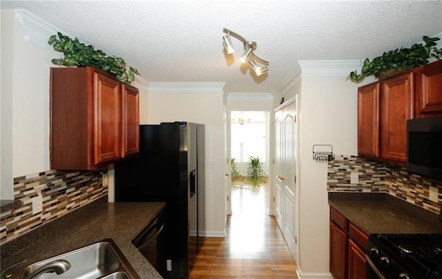 kitchen with dark countertops, ornamental molding, wood finished floors, and a sink