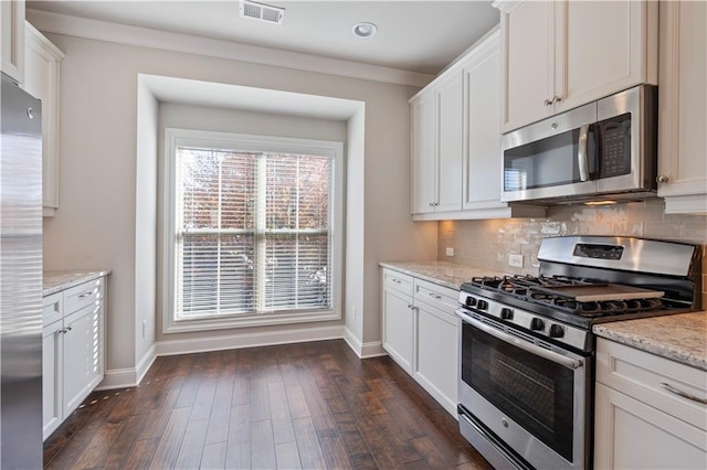 kitchen with white cabinets, appliances with stainless steel finishes, light stone counters, and dark wood-type flooring