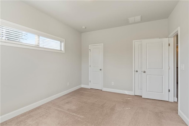 unfurnished bedroom featuring light colored carpet and a closet