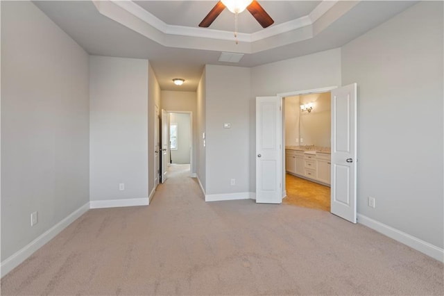 unfurnished bedroom with light carpet, connected bathroom, a raised ceiling, and ceiling fan