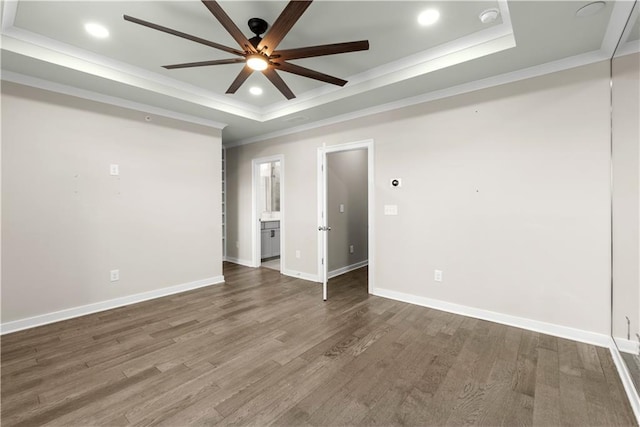 spare room featuring a tray ceiling, dark wood-type flooring, and ornamental molding