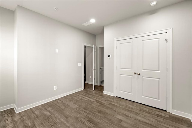 unfurnished bedroom with dark hardwood / wood-style flooring and a closet