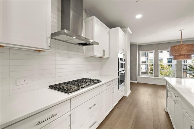 kitchen featuring white cabinets, wall chimney range hood, decorative backsplash, appliances with stainless steel finishes, and dark hardwood / wood-style flooring