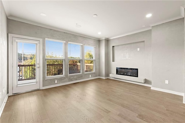 unfurnished living room with a healthy amount of sunlight, ornamental molding, and light hardwood / wood-style flooring