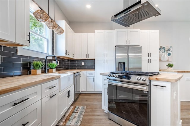 kitchen with white cabinetry, appliances with stainless steel finishes, and butcher block countertops