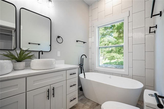 bathroom featuring a washtub, hardwood / wood-style floors, toilet, and vanity