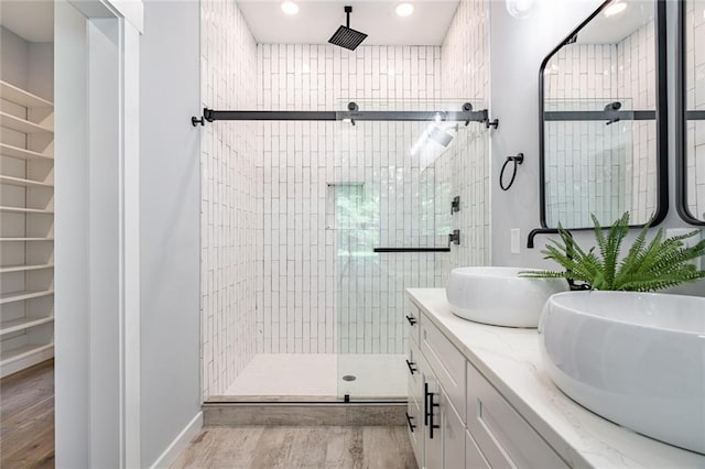 bathroom featuring wood-type flooring, a shower with door, and vanity