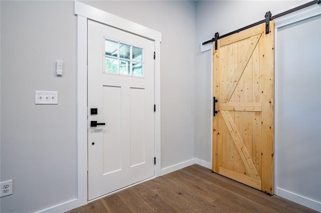 foyer entrance with a barn door and dark hardwood / wood-style flooring