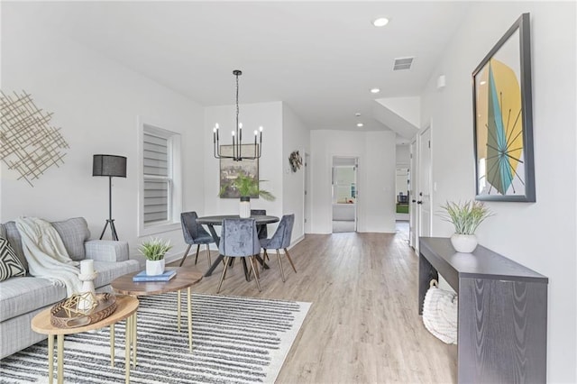 living room featuring light wood finished floors, visible vents, a notable chandelier, and recessed lighting