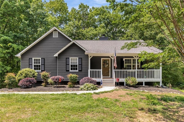 ranch-style house featuring covered porch, a chimney, and a front lawn