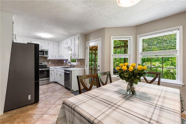 kitchen featuring appliances with stainless steel finishes, tasteful backsplash, a sink, light tile patterned floors, and light countertops