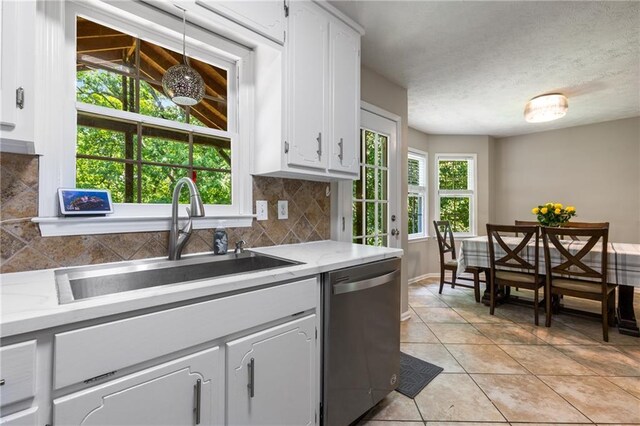 kitchen with a sink, decorative backsplash, stainless steel dishwasher, and white cabinets