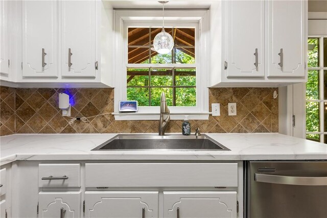 kitchen with a sink, stainless steel dishwasher, white cabinetry, and decorative light fixtures