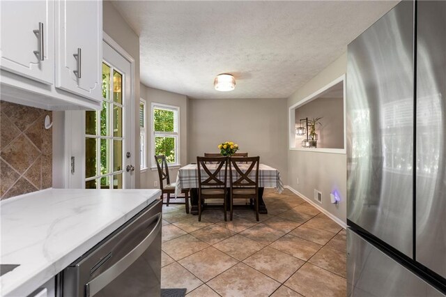 dining space with light tile patterned flooring, baseboards, and a textured ceiling