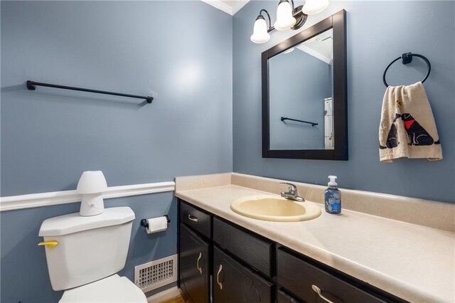 bathroom featuring visible vents, crown molding, toilet, and vanity