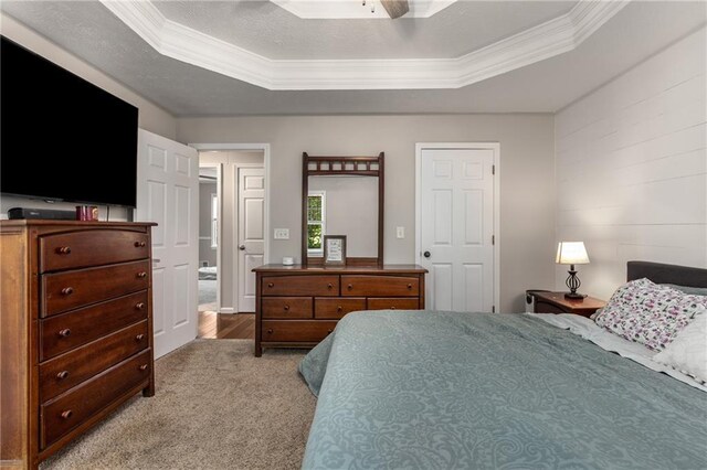 carpeted bedroom featuring ornamental molding, a ceiling fan, and a tray ceiling